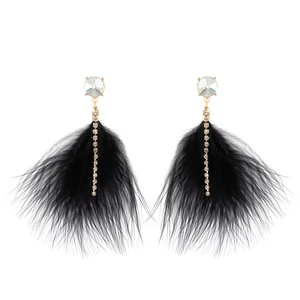 Close-up of black feather earrings with gold plating and sparkling crystal details