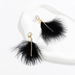 Close-up of elegant long black feather earrings with sparkling crystals and gold chains