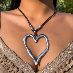 Dettaglio del grande ciondolo a cuore irregolare su una collana in corda marrone regolabile
