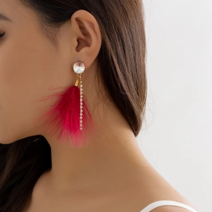 Close-up of model wearing long red feather tassel earrings with white pearls and rhinestones
