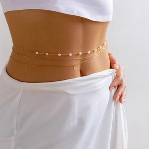 Detail view of gold layered waist chain with pearls and round pendant on model