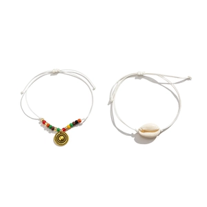 Detalle de tobilleras bohemias con concha, colgante de sol y cuerdas ajustables
