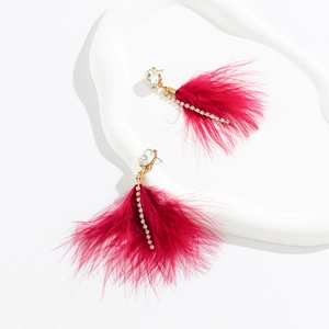 Detail of bohemian drop earrings featuring vibrant magenta feathers and sparkling crystals