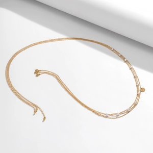 Close-up of golden layered snake chain belt with white pearls and cross pendant details