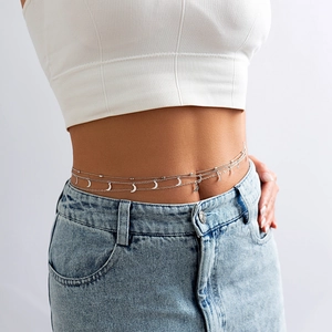 Detail der mehrlagigen silbernen Körperkette mit Mondanhängern auf heller Jeans