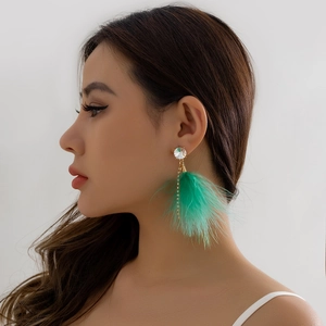 Detail of vibrant green feather drop earrings with gold chains on a fashion model