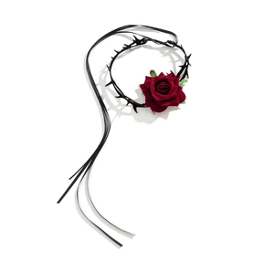 Detail van een gothic choker met donkerrode fluwelen roos en zwarte satijnen linten