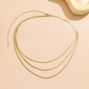 Detail of triple-layered golden snake chain with adjustable clasp on a pink background