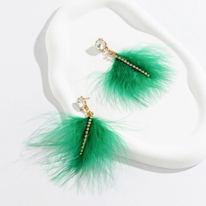 Detail of elegant gold earrings with bright green feathers and sparkling crystal stones
