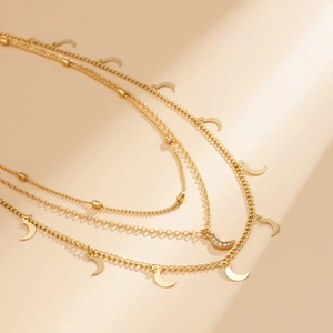 Detailaufnahme einer mehrlagigen Goldkette mit Mondanhängern und funkelnden Zirkonsteinen