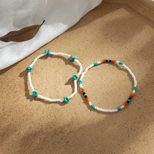 Detalle de tobilleras bohemias de turquesa en una bandeja con sombras naturales suaves