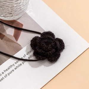 Macro-opname van de zwarte gehaakte bloemenchoker met gelaagde textuur en zacht touw