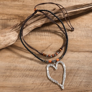 Dettaglio di un grande ciondolo a cuore su una collana bohémien a doppio cordoncino
