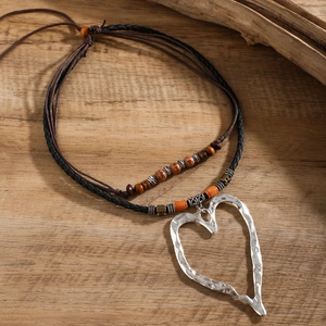 Dettaglio del ciondolo a cuore con perle di legno su collana a doppio cordoncino