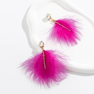 Detail view of fuchsia long earrings with rhinestones and feather tassel on white tray
