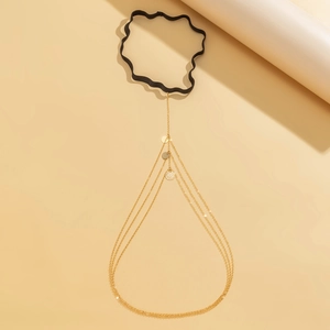 Detail of a black elastic garter leg chain featuring three layers of gold metal chains