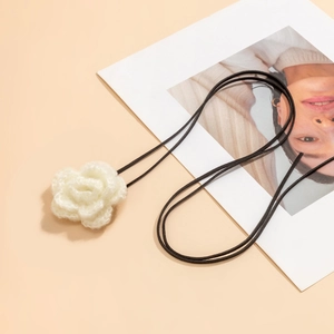 Detail van handgehaakte witte bloemhanger aan een zwart smal fluwelen choker-koord
