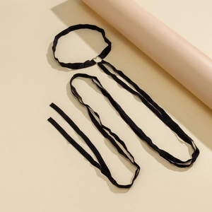 Close-up of black elastic leg chain with a silver metal ring connector on a beige backdrop