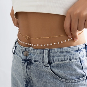 Nahaufnahme der zweilagigen goldenen Taillenkette mit Perlen und Schmetterling auf Jeans