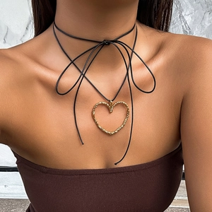 Dettaglio ravvicinato della collana choker con grande cuore dorato e trama a corda