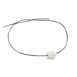 Macro-detail van de witte gehaakte bloemhanger op een minimalistische zwarte halsband