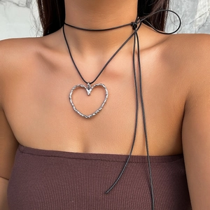 Dettaglio del ciondolo a cuore in argento traforato su girocollo nero in velluto su modella