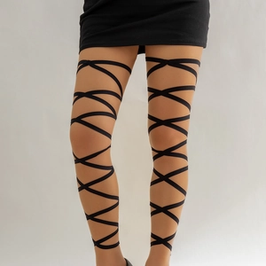 Close-up of gothic style black ribbon cross straps on beige thigh high leg chain accessory