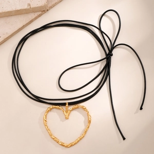 Dettaglio di un grande ciondolo a cuore dorato strutturato su una collana choker nera