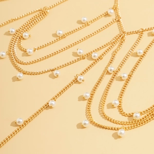Detail of layered gold body chain with white pearls and butterfly tassels for beachwear