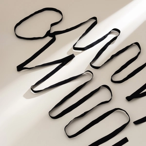 Close-up of black elastic leg chain strap with a sleek satin finish on a beige background