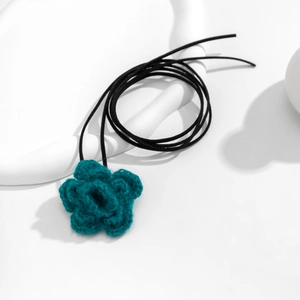 Close-up van handgemaakte gehaakte bloem choker in petrolkleur op een witte houder