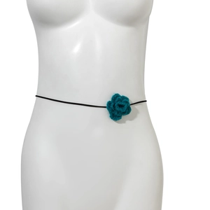 Detail van blauwe handgemaakte gehaakte bloem met zwart koord voor damesaccessoire