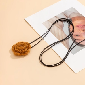 Detail van een handgemaakte gehaakte roos choker met bruin garen en zwart suède koord