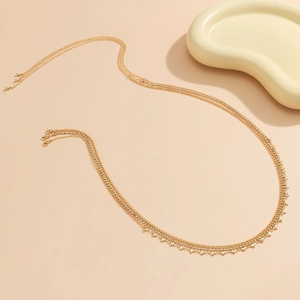 Détail d'une chaîne de corps dorée multicouche avec strass et petits charms cœur
