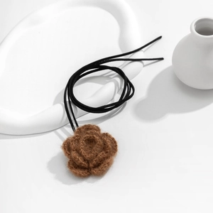Macro-opname van handgemaakte bruine gehaakte roos hanger aan een fluwelen choker