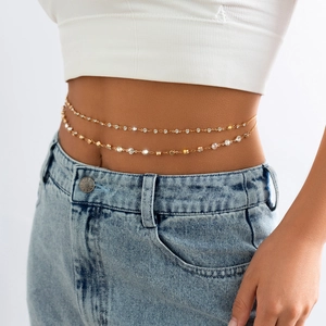 Detail einer böhmischen goldenen mehrlagigen Bauchkette mit Strass auf einer Jeanshose
