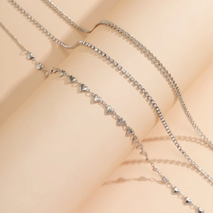 Gros plan d'un ensemble de chaînes argentées avec cœurs, strass et maille gourmette
