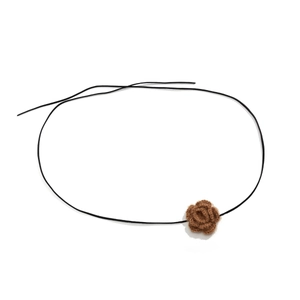Detail van een handgemaakte bruine gehaakte bloem op een zwarte koord choker ketting