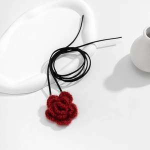 Detail van een handgemaakte rode gehaakte roos choker met lange zwarte koordjes