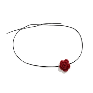 Detail van rode gehaakte rozenbloem choker aan zwart waxkoord in vintage handwerkstijl