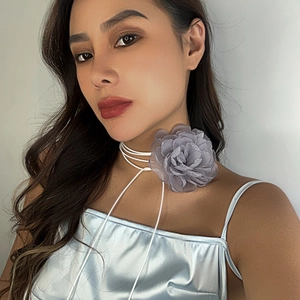 Close-up of a large smoke grey floral fabric choker necklace with white tassel tie lace