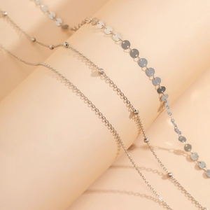 Détail de trois chaînes de corps argentées avec paillettes, perles et maillons épurés