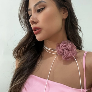 Close-up of a dusty pink silk camellia flower choker with long white ribbons for women