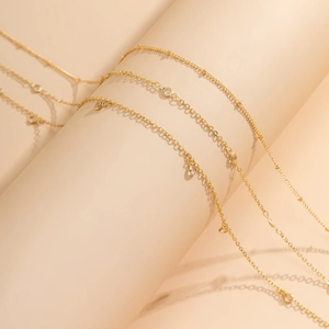 Détail d'une chaîne de taille dorée avec pendentifs en zircon sur support rose