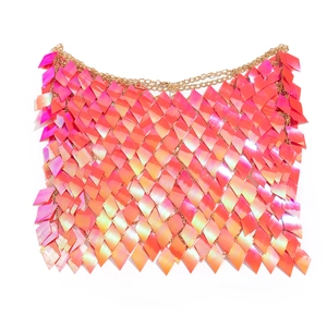 Detail of pink iridescent diamond sequins and gold metal chain link body jewelry