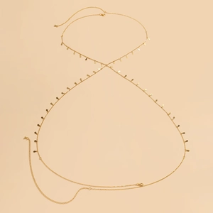 Detail einer goldene Körperkette mit Karabinerverschluss und Tropfenanhängern