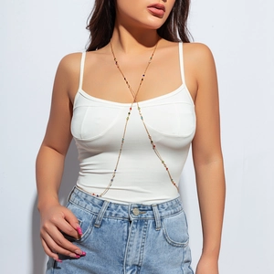 Detail einer goldenen Körperkette mit bunten Perlen über einem weißen Tanktop