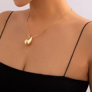 Polished gold teardrop pendant necklace closeup showing a glossy finish on a model