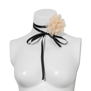 Detail of a beige chiffon fabric flower on a black ribbon choker displayed on a white bust
