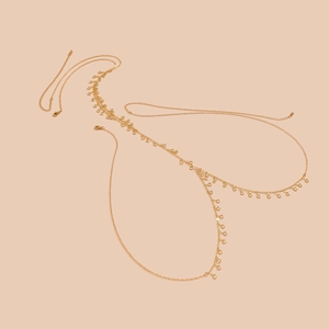 Detailaufnahme der goldenen Kristall-Körperkette mit Schmetterlings-Strass auf Beige